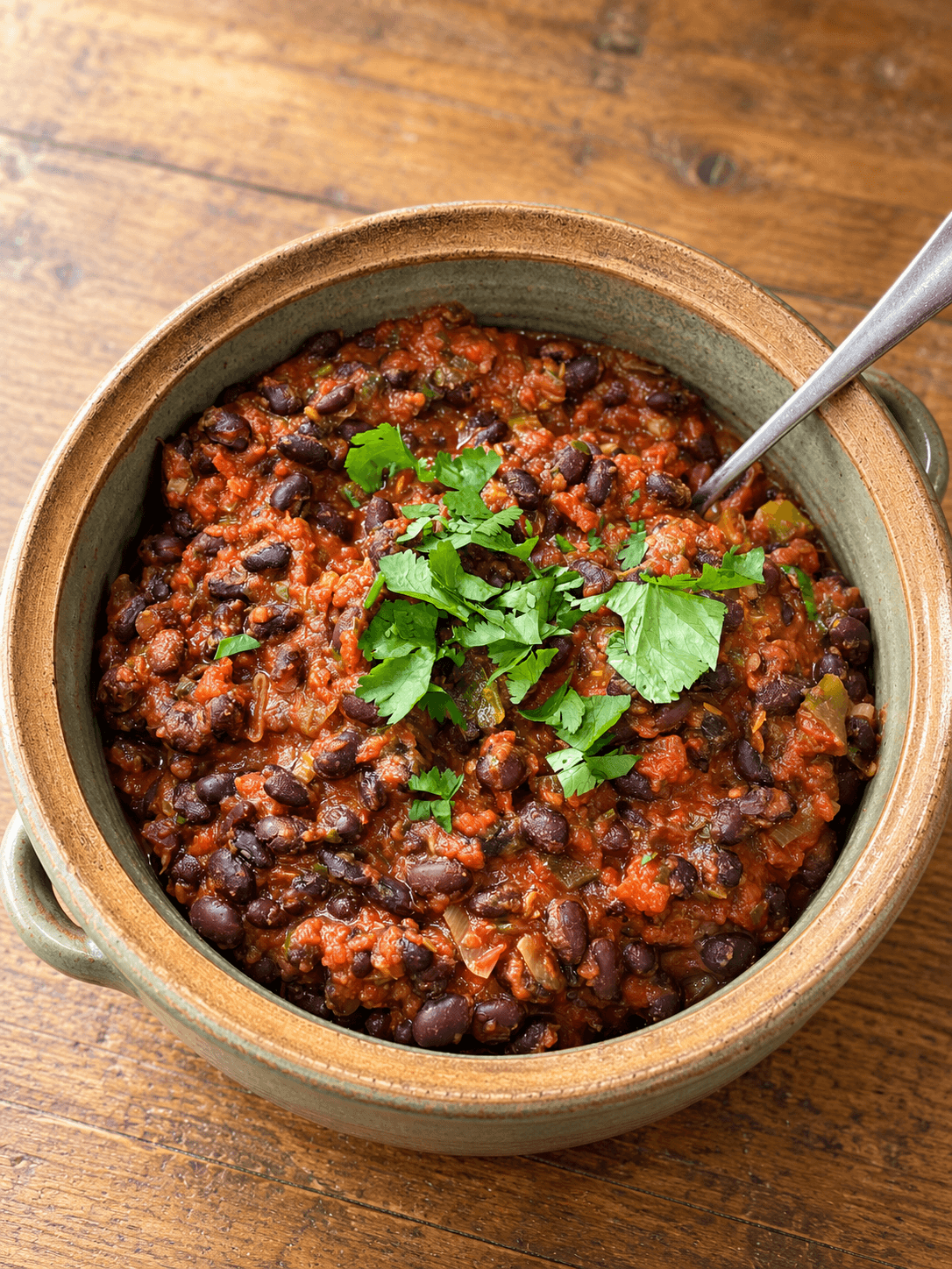 Black bean chilli with tomatoes and spring onions in a shallow bowl